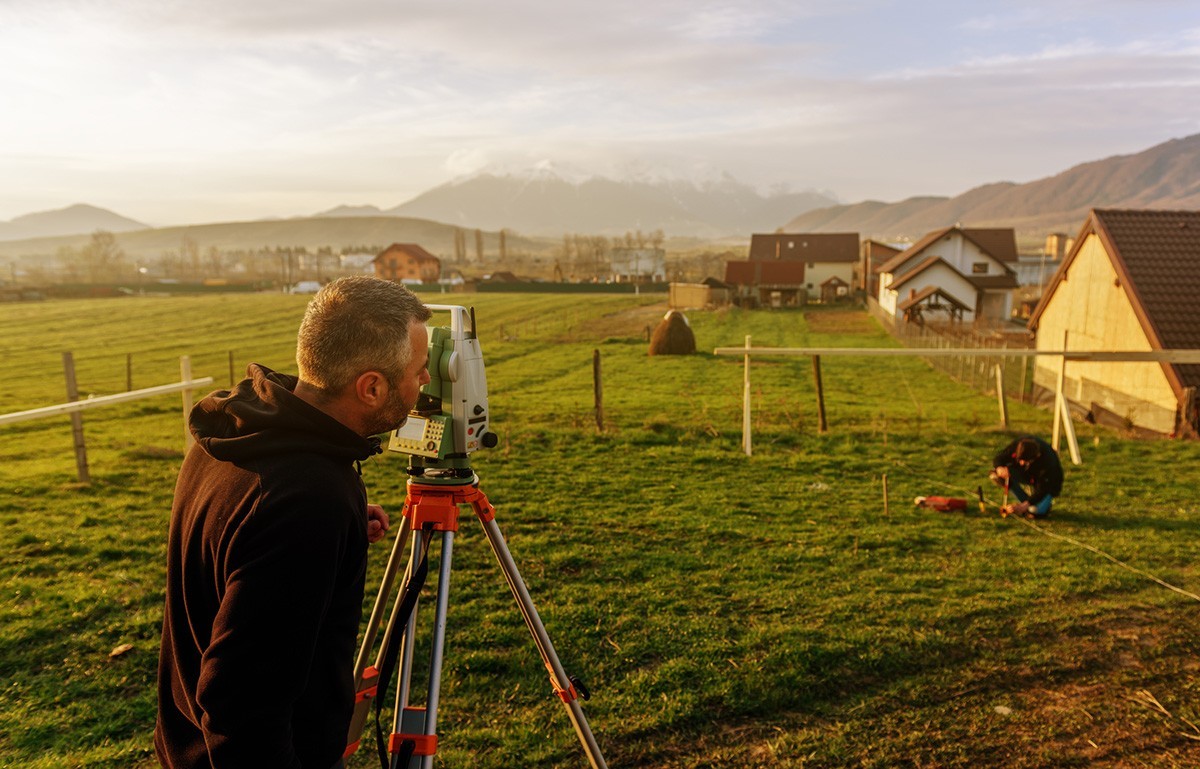 Two people conducting a land survey on a farm.