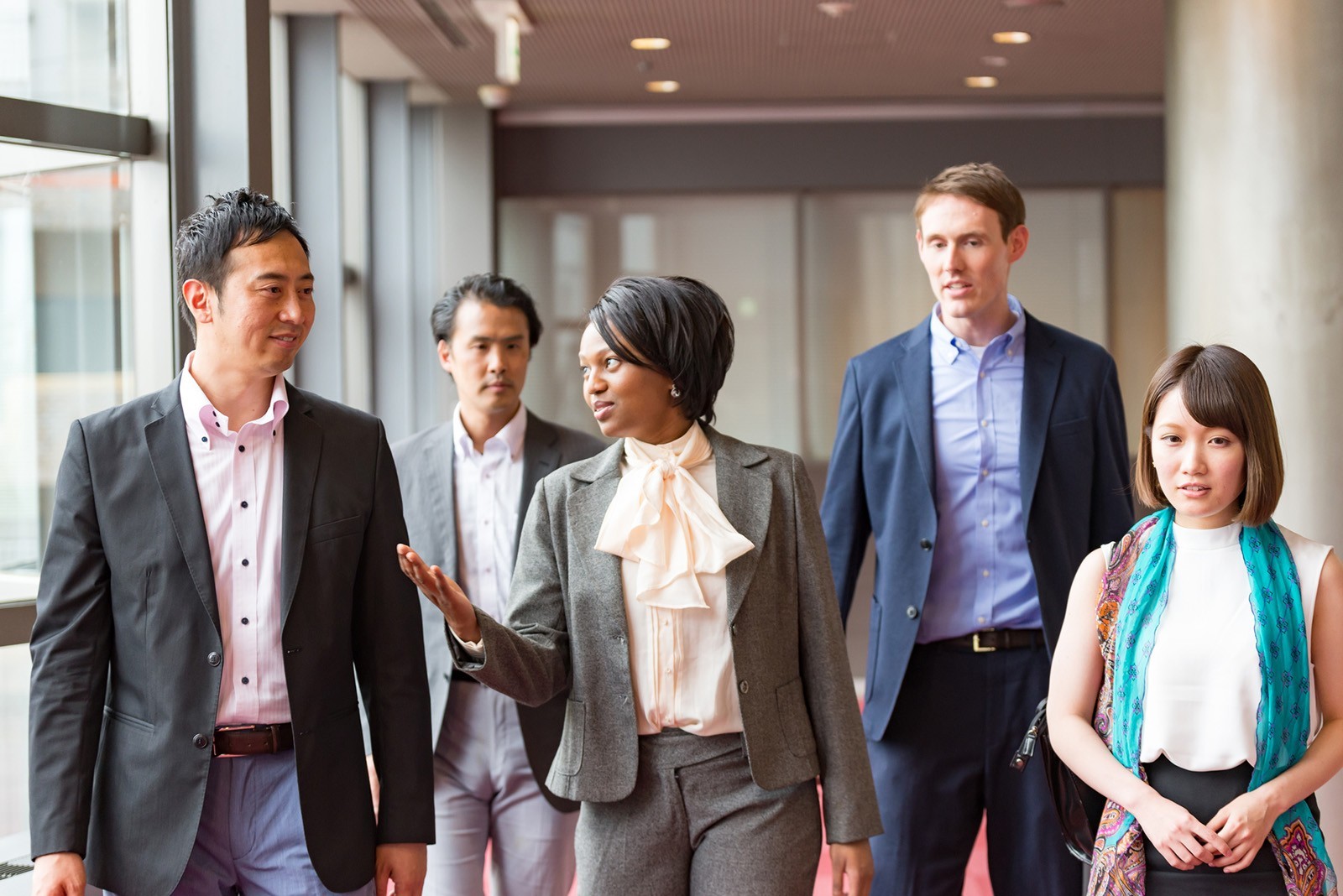 A group of international business people walking together in an office hallway