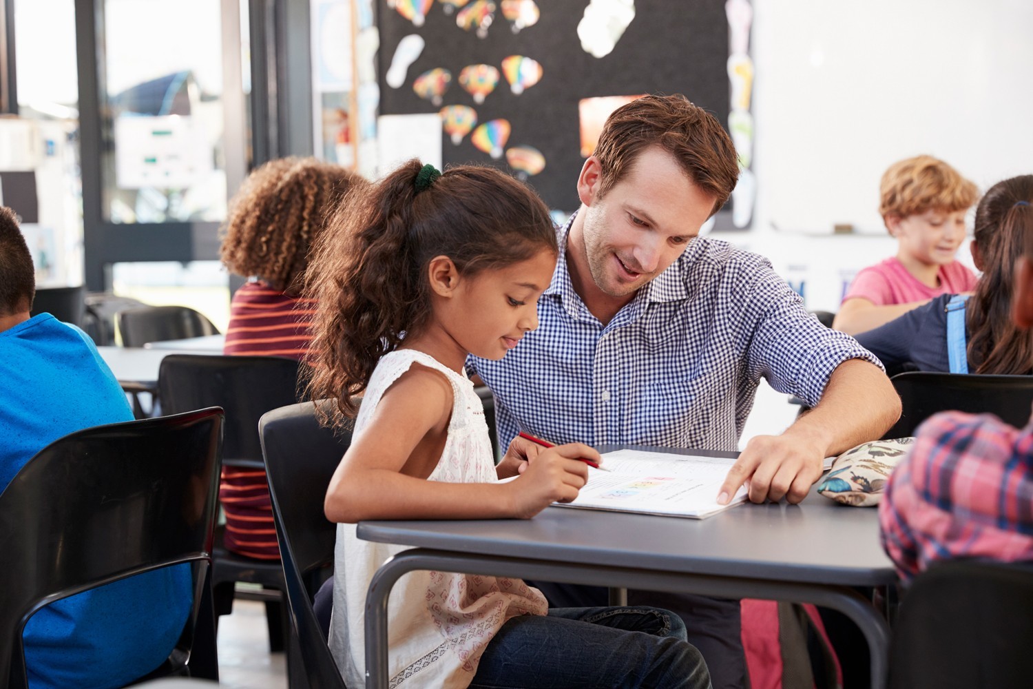 A teacher working with a young student in classroom.