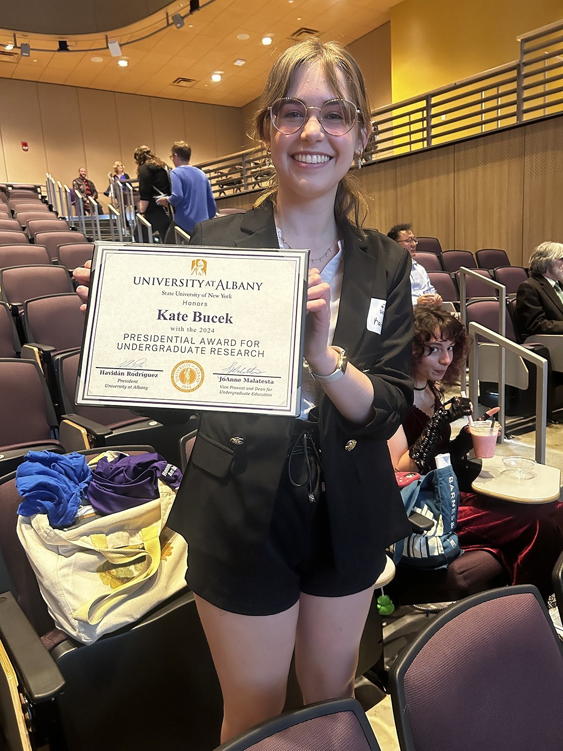 UAlbany student Kate Bucek shows her presidential award in the auditorium at the Campus Center