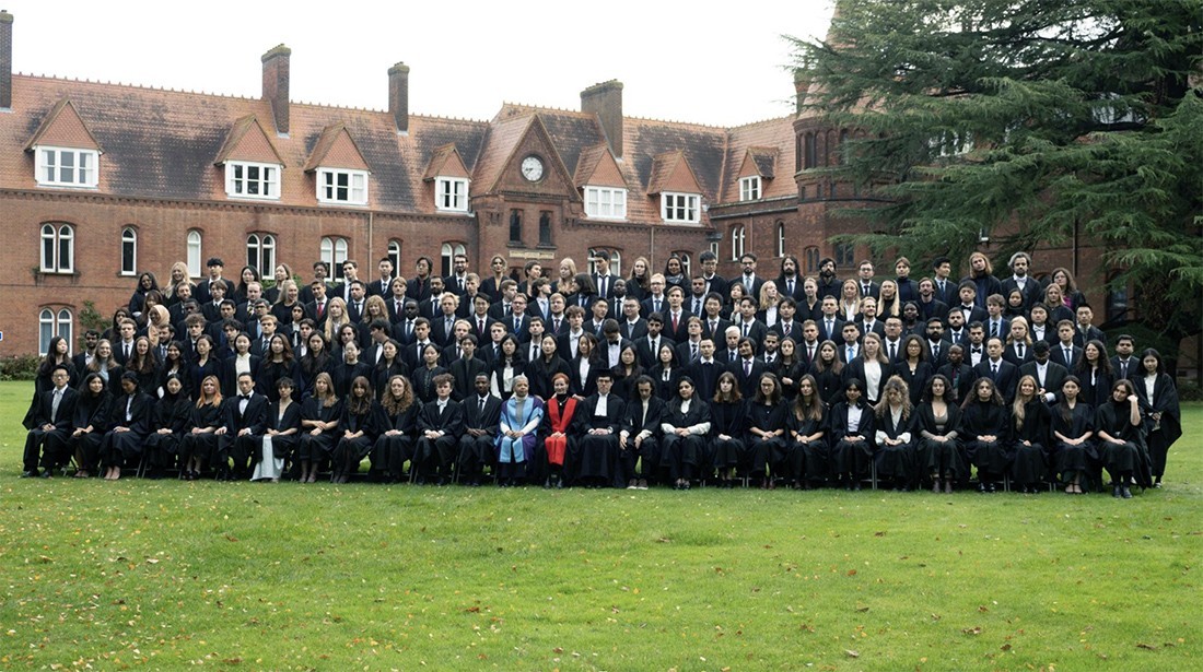 A large group of students at the University of Cambridge pose for a picture in the campus quad.
