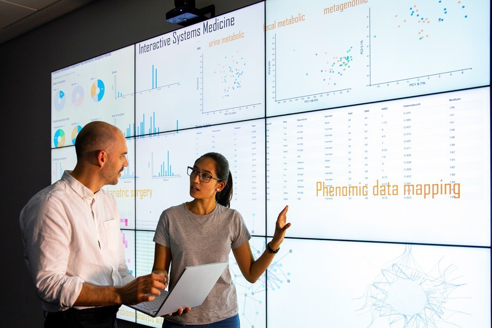 Two professionals viewing multiple screens of data