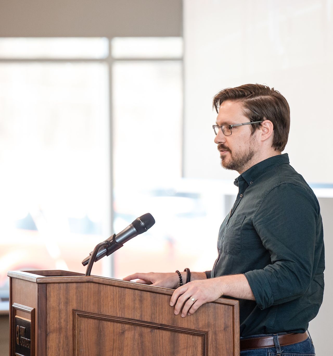 A man with a beard and glasses stands at a podium
