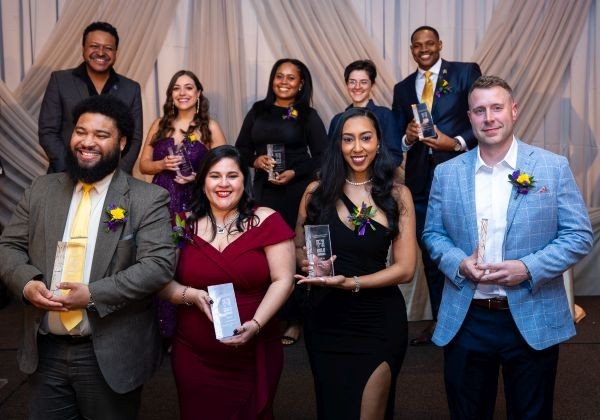 a group of smiling. dressed-up people hold awards