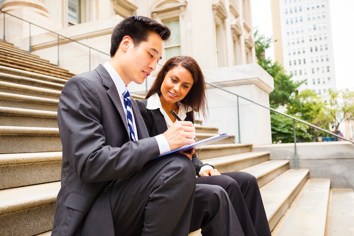Two attorneys having a discussion on the steps of a law firm