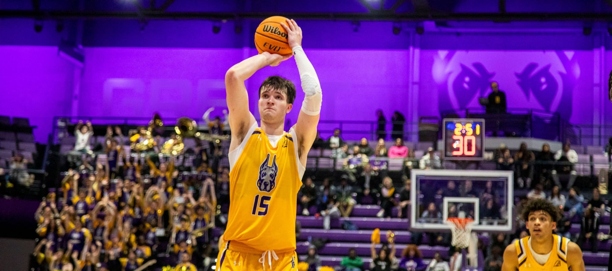 A UAlbany men's basketball player leaps just before shooting the ball to the hoop.