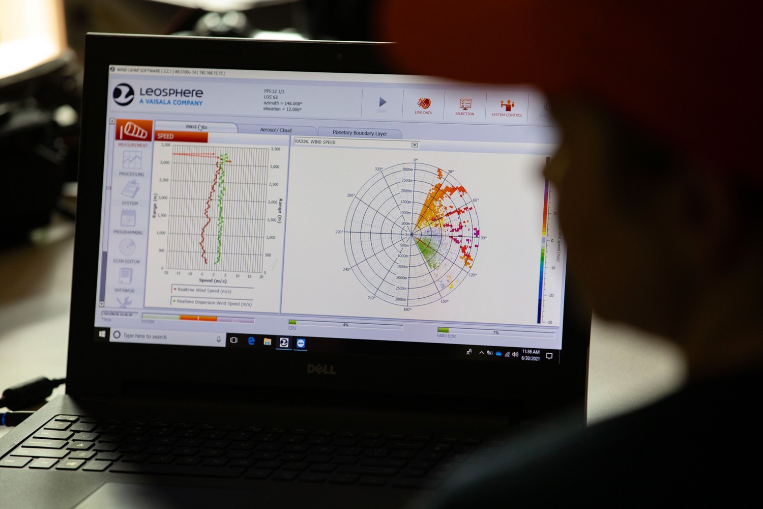 A researcher looking at radial wind speed data charts on a laptop.