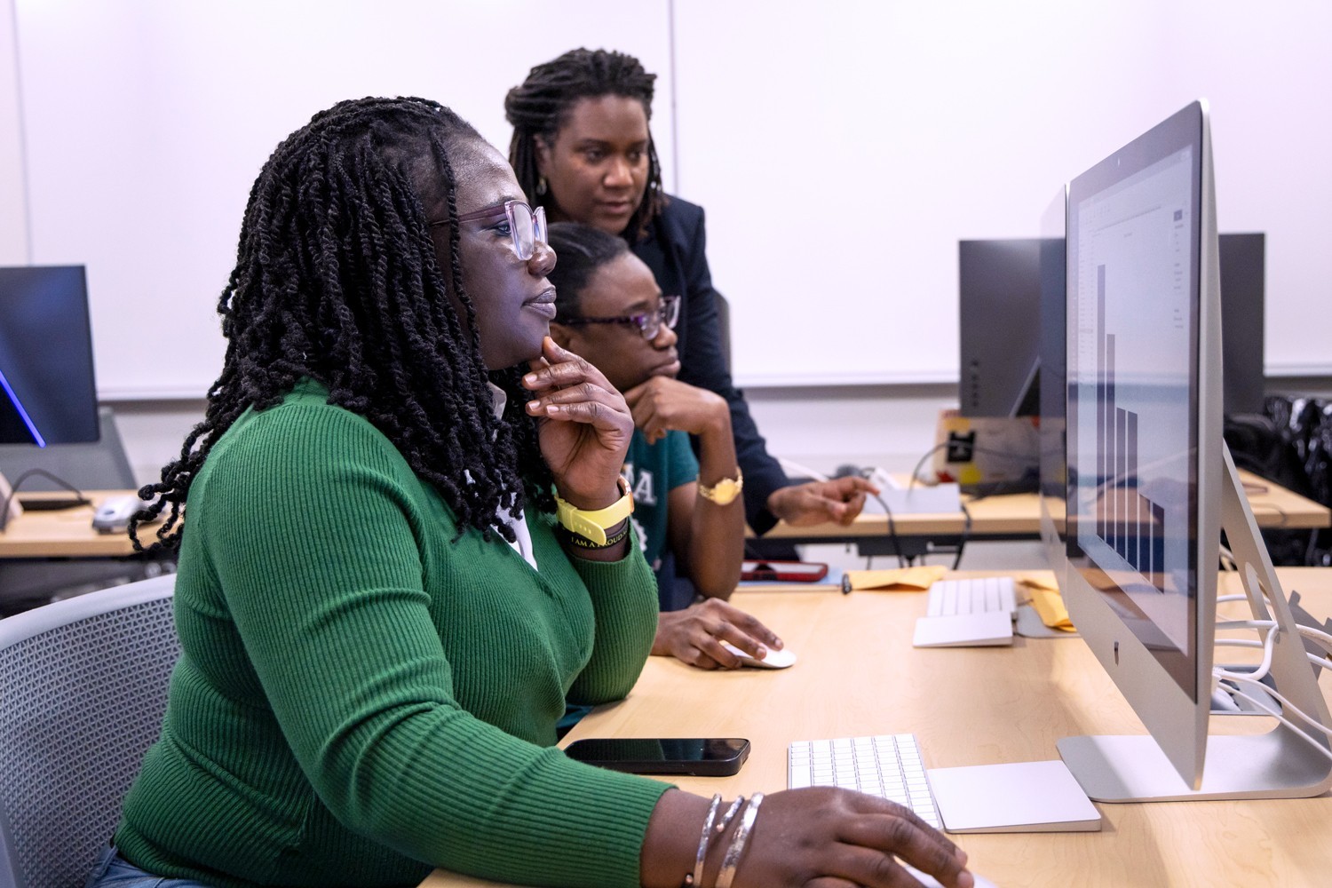 A professor working with two students at computers.