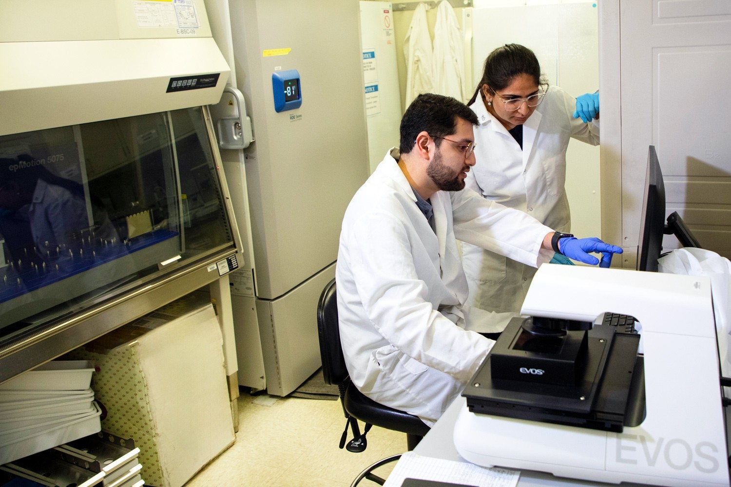 Two researchers in a UAlbany nanotechnology lab looking at data on a computer.