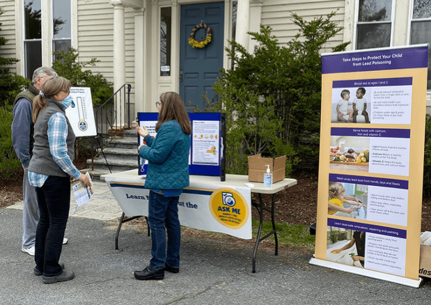 Three people standing in front of a table that has information.