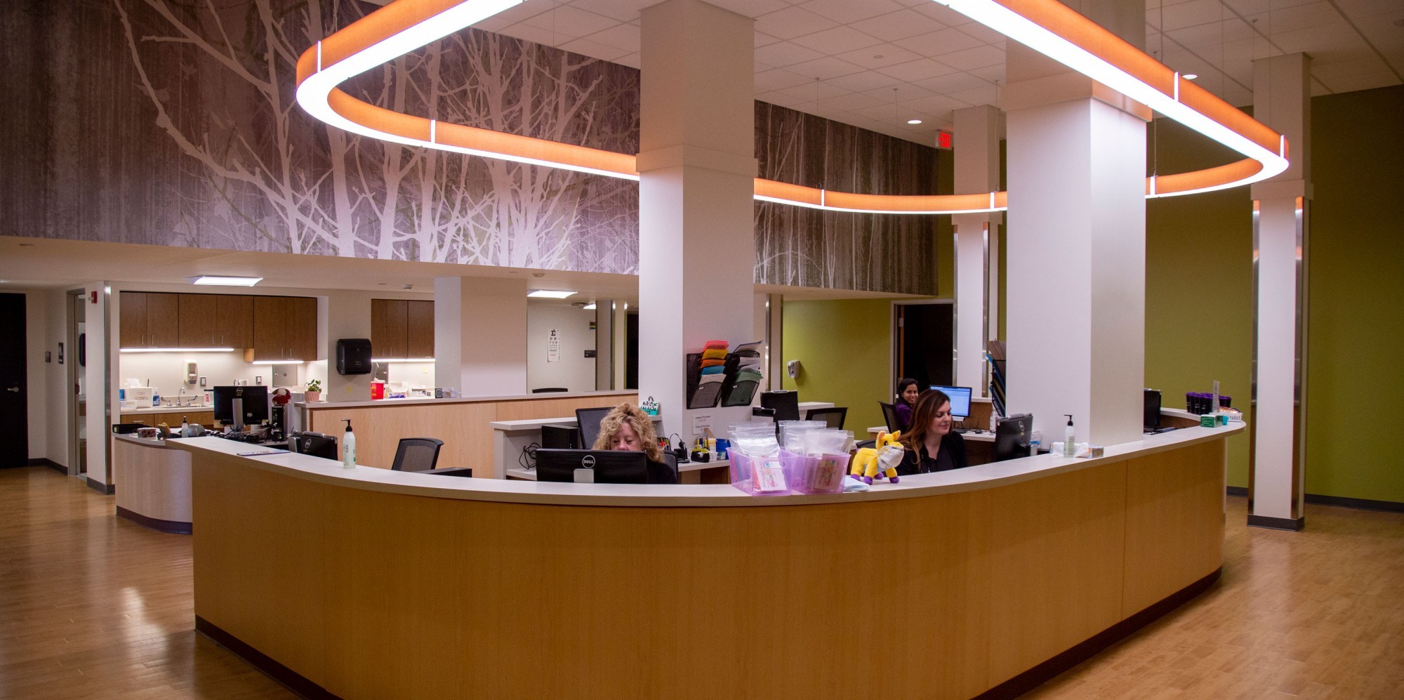 Two staff members sit inside a U-shaped nurses station inside the Student Health Services clinic.