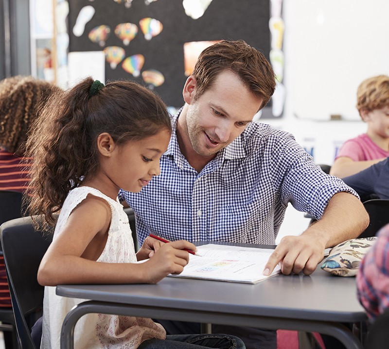Teacher helping a student read in class