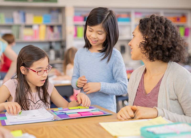 Teacher helping two young students