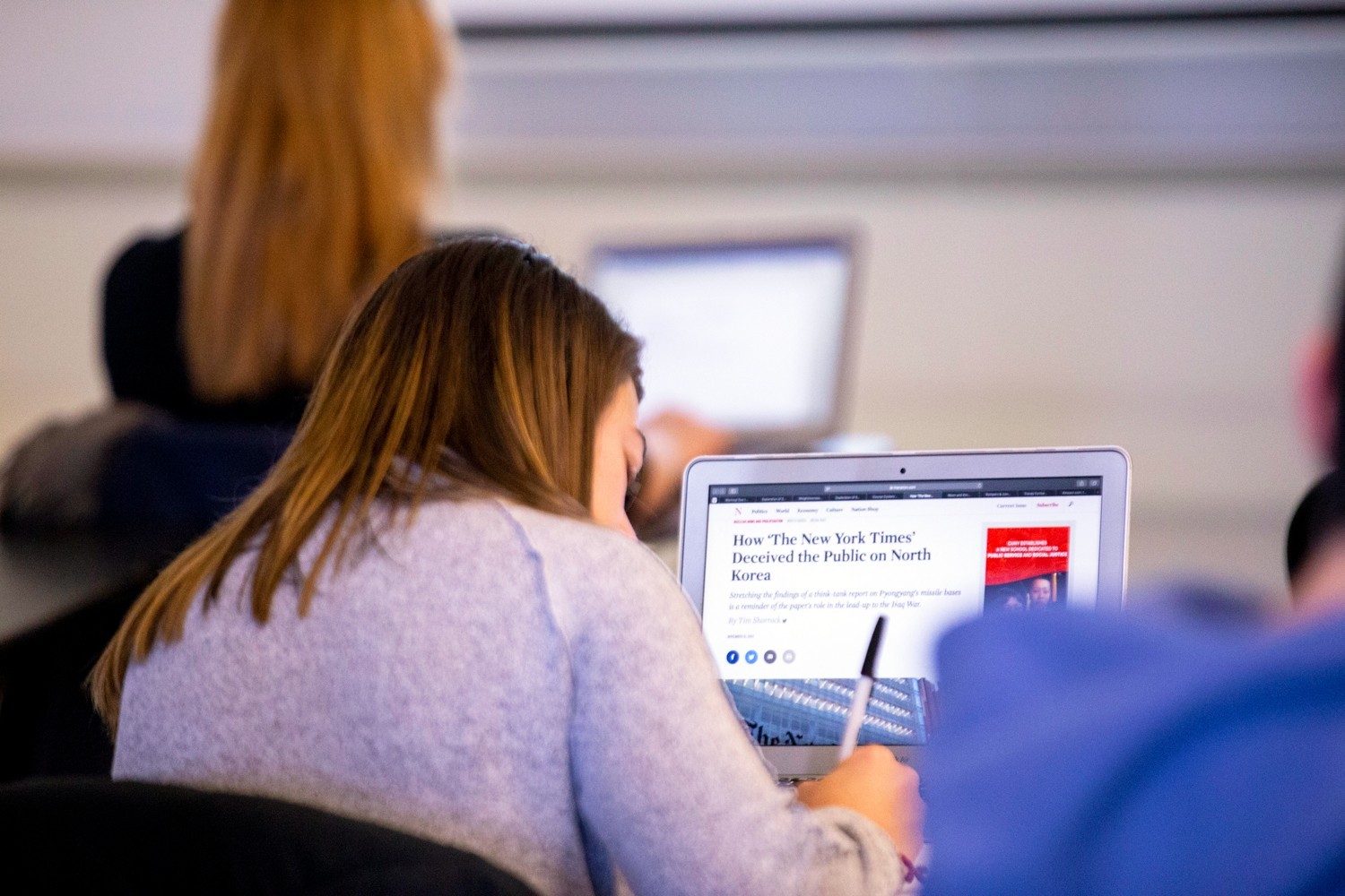 A UAlbany journalism student researches a newspaper article on her laptop