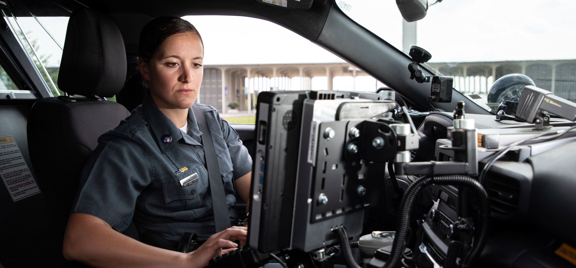 A UPD officer sits in the driver's seat of her squad car and types on the computer.