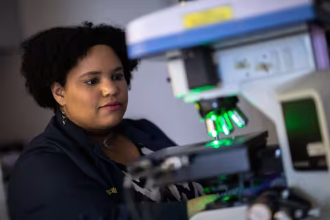 A researcher works in front of a microscope inside a scientific laboratory.