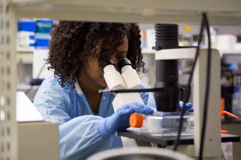 A student using a microscope in a research lab.
