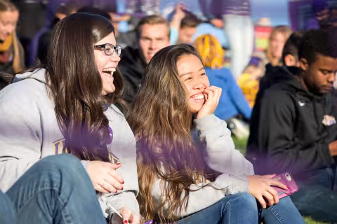 Two students sit together on a sunny homecoming day