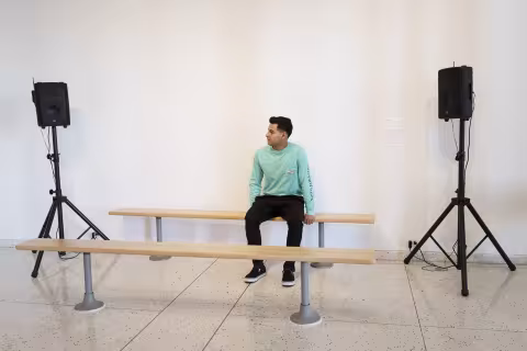 a person sitting on a bench with a bench in front of them and a speaker on a pole on both sides
