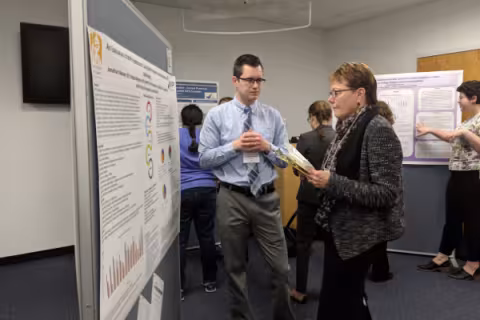 A student speaks to a judge about his poster.