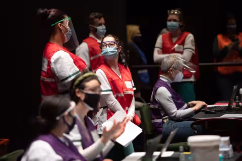 Volunteers working at the vaccine POD on campus, some standing and some sitting.