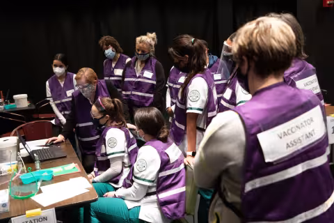 Volunteers gathered around a computer at the vaccine POD on campus.