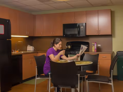 A student eats cereal and reads the newspaper inside a Liberty Terrace apartment's kitchen