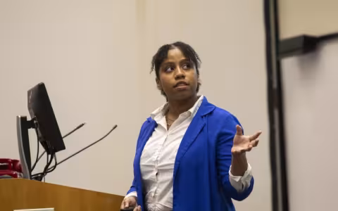 Sydney Hanson, a student researcher at The RNA Institute, stands at a podium and presents as part of the Summer Research Program Symposium at UAlbany.