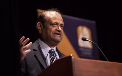 A tight shot of Vice President for Research Thenkrussi "Kesh" Kesavadas standing at podium framed in the background by a UAlbany banner.