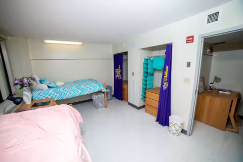 A double bedroom with two twin beds, two desks, two dressers and two closets.