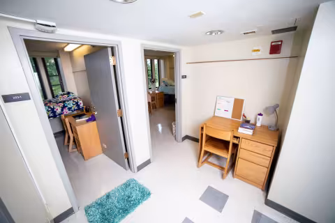 The entryway of a residential suite, with a desk and two doorways leading to bedrooms.