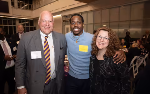 UAF board member Lew Wiener poses smiling with senior finance major Semi Awopetu and Alumni Association President Jill Delaney at the scholarship dinner in ETEC's atrium. 