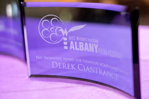 A close-up of a curved glass award honoring director Derek Cianfrance with NYSWI's Ironweed Award.