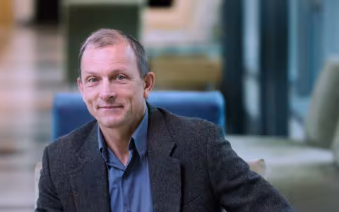 A portrait of Distinguished Professor Igor Lednev seated wearing a dark gray sport coat and blue shirt.