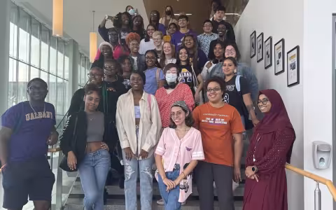 A group of about 40 student educators pose on a staircase in the Massry Center for Business.