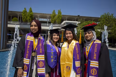 Four female students in regalia on campus.