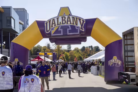 Students walking under UAlbany arch at Homecoming. 