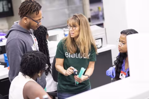 A professor is talking to three students in a lab in the Life Sciences Building. 