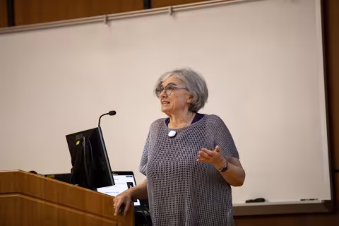 Marlene Belfort delivers her keynote talk standing at a podium. 