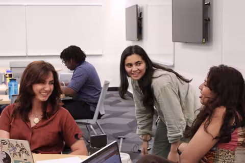 Three students smile during research presentations of Md. Aynul Bari's NSF summer research team.
