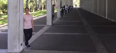 Members of The Wang Group stand alongside UAlbany's distinctive white pillars that extend into the distance
