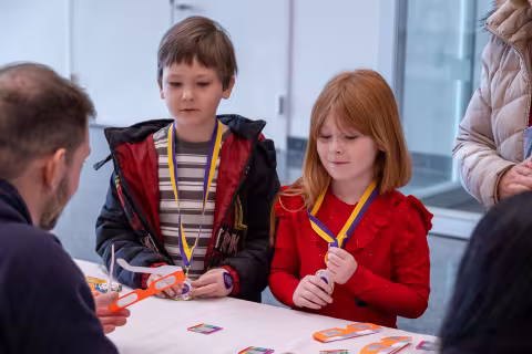 A young boy and girl listen to scientists talk at UAlbany's STEM & Nanotechnology Family Day at ETEC.