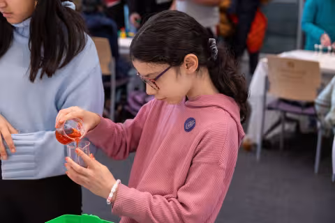 A girl conducts an experiment with a colorful liquid at UAlbany's STEM & Nanotechnology Family Day at ETEC.