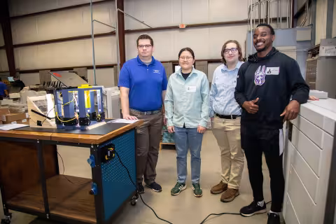 Alex Demitraszek, Jordan Jung, Jacob Bruno and Shak Williams stand next to their new device at the mail facility in Colonie, N.Y.