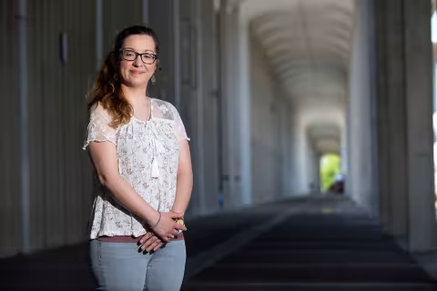 Assistant Professor of Electrical and Computer Engineering Daphney-Stavroula Zois poses standing with her arms crossed in front of her beneath the arches of UAlbany's Academic Podium.