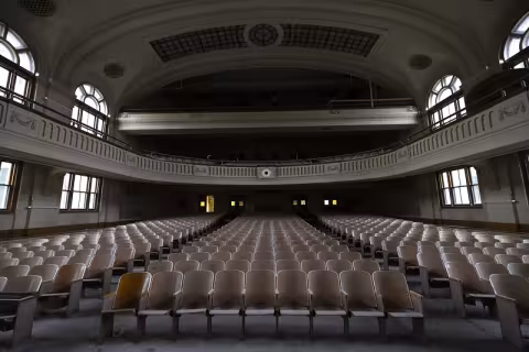 A photo of an unrenovated, century-old three-level auditorium taken from the stage facing the seats.