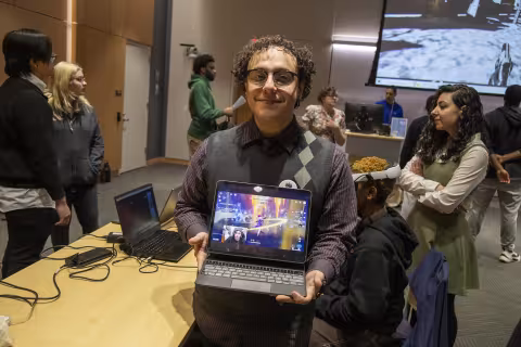 A UAlbany student shows his laptop with his research at Showcase Day 2024 inside ETEC.