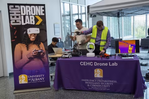 Presenters stand next to a poster of the Drone Lab at ETEC during Showcase Day 2024.