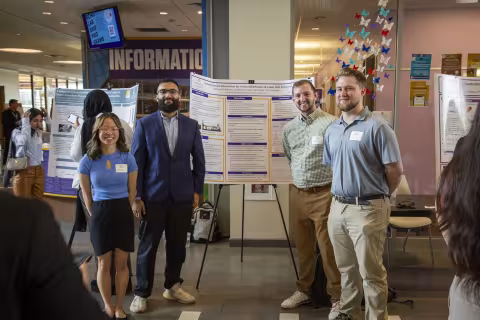 Four students stand by their poster during Showcase Day 2024.