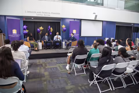 A group of students present their work while seated at the Massry Center for Business Standish Living Room during Showcase Day 2024.